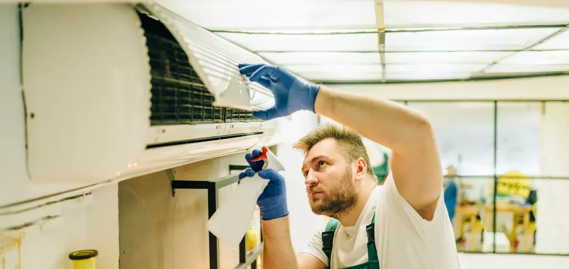 technicien entrain de nettoyer une thermopompes murale